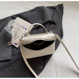 Detail of creamy white textured handbag showing silver zipper and brown fabric lining