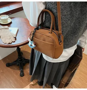 Detailed side view of brown Boston pillow bag with a small Trojan horse charm