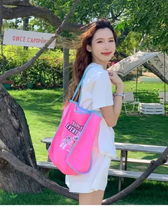 Détail du sac cabas en toile rose avec motif dessin animé et bordure bleue en plein air