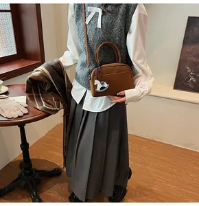 Close-up of retro brown leather crossbody bag with a white rocking horse charm accessory