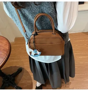Brown PU Boston bag detail showing top handles and a cute rocking horse charm