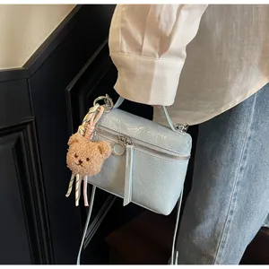 Detail of light blue cracked texture handbag featuring a cute brown plush bear charm