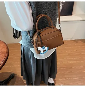 Detail of vintage brown leather handbag with a horse pendant and adjustable shoulder strap