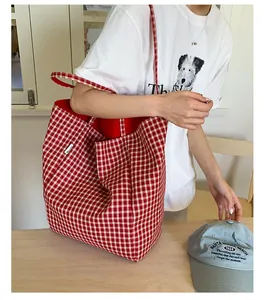 Close-up of red and white checkered canvas tote bag with casual lifestyle outfit
