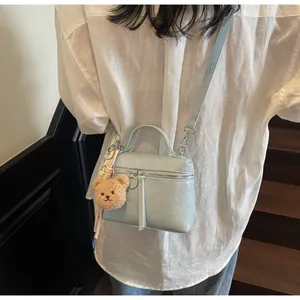 Back view of model wearing a light blue glossy mini bag with a teddy bear charm