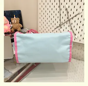 Gros plan d'un sac cabas en toile bleu clair avec poignées roses et finitions contrastées