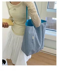 Detail of blue and white gingham tote bag with light blue lining and brand label