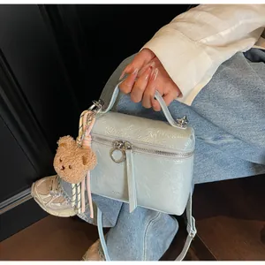 Detail of light blue box handbag with patent leather texture and cute brown bear pendant