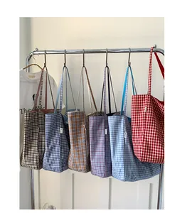 Showcase of six various plaid canvas tote bags hanging on a metal rack in a studio setting