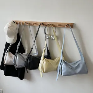 Minimalistische weiche Ledertaschen in fünf Farben an einer Wand für den Sommerstil 2025
