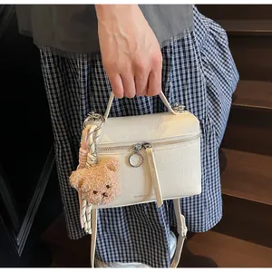 Close-up of cream white textured mini tote bag with cute brown plush bear charm detail