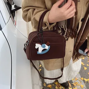 Retro dark brown half-moon pillow bag with horse charm shown in a cozy autumn setting
