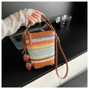 Detail of colorful woven bucket bag with leather handles and strawberry charms