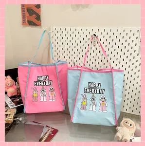 Détail de cabas en toile bicolores avec imprimés de dessins animés et bandoulières