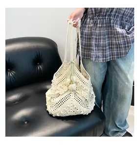 Detail of cream crochet tote bag featuring floral tulip charms and textured wavy edges