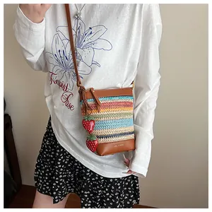 Detail of colorful woven straw bag with strawberry charms and leather shoulder strap