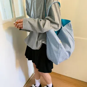 Large blue and white checkered canvas tote bag worn over the shoulder by a model