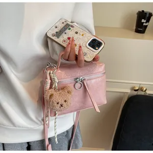 Pink embossed leather handbag detail with silver ring zipper and cute bear charm accessory