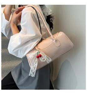 Detail of light pink patent leather handbag with cherry charms and lace bow accessories