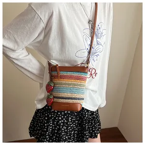 Detail of rainbow woven bucket bag featuring strawberry charms and leather base