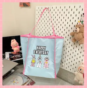 Détail du sac fourre-tout bleu clair avec anses roses et graphismes de dessins animés