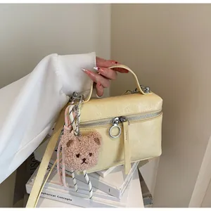 Detail of yellow wrinkled leather handbag with silver zipper and brown bear charm
