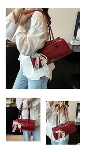 Detail view of burgundy leather shoulder bag with cherry lace pendant and sleek straps
