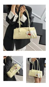Detail view of cream rectangle handbag featuring cherry charm and fashion lettering