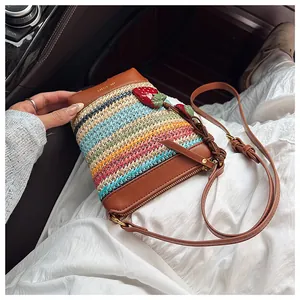 Detail of woven bucket bag with leather trim and red strawberry charms in a car interior