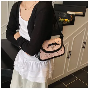 Detail of pink pleated crossbody bag with black bows and heart pendant on model