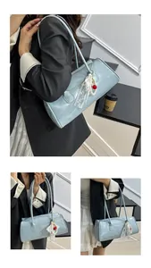 Close-up of light blue patent leather bag with lace, pearl and cherry pendant detail