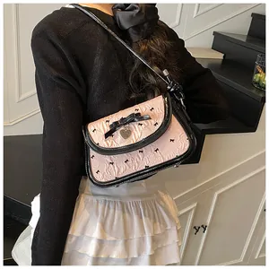 Rear view of a balletcore pink ruffled crossbody bag with black bow patterns and accents