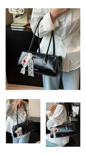 Detail of black glossy handbag featuring white lace cherry ribbon and side text print