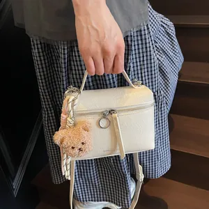 White crackle-textured handbag with plush bear charm and rainbow strap for women