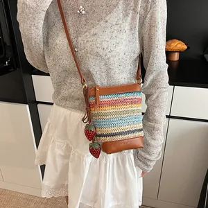 Colorful woven striped bucket bag with brown leather trim and cute strawberry pendants