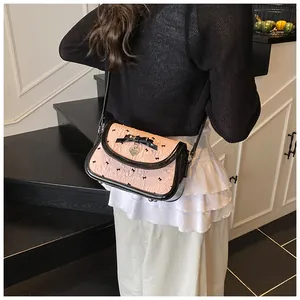 Detail of pink bow-knot crossbody bag with heart pendant worn by a model in lifestyle shot