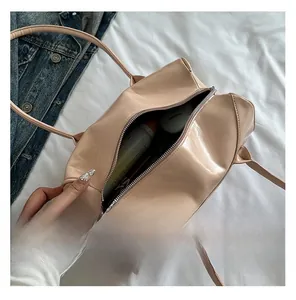 Top view of a beige glossy handbag showing spacious interior with cosmetic items