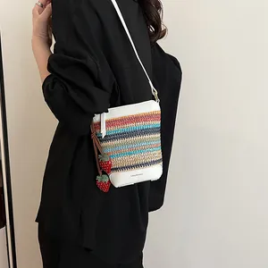 Woven straw bucket bag with colorful stripes, white trim, and strawberry charms