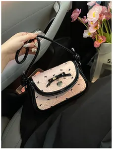 Detail of pink embossed shoulder bag with black bow embroidery and heart pendant