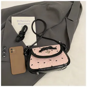 Detail of pink ruffled fabric crossbody bag with black bow and heart-shaped silver pendant