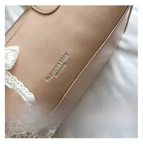 Detailed macro view of beige textured leather handbag with elegant white lace trim detail