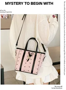 Détail du sac cabas rose avec nœuds, pendentif en forme de cœur et bandoulière noire