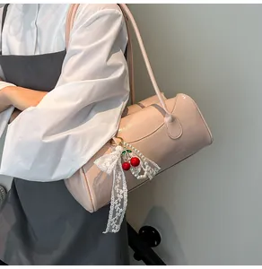 Detailed view of light pink cylindrical shoulder bag with a designer cherry charm