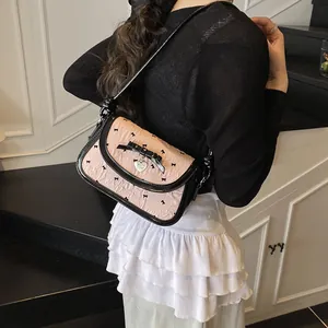 Pink bow shoulder bag with black trim and heart pendant shown on model