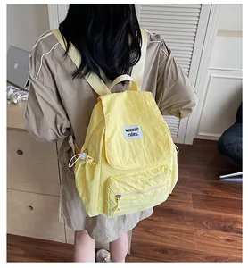 Detail of bright yellow nylon backpack featuring a woven label and drawcord side pockets