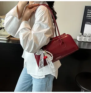 Detail of wine red glossy handbag with lace bow, pearls, and cherry charms
