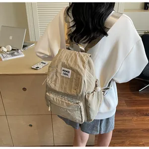 Detail of beige wrinkled nylon backpack featuring flap closure and branded white woven label