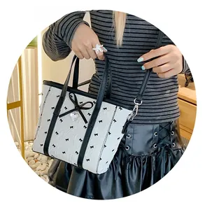 Détail du mini sac blanc avec motifs de nœuds noirs, pendentif cœur et bandoulière
