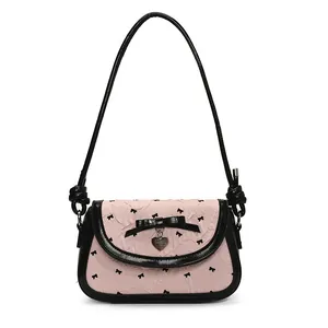 Pink textured shoulder bag with black bows and heart pendant on white background
