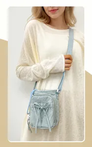 Detalle de bolso bandolera de nailon azul claro con cordón de lazo y bolsillo con cremallera